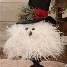 an odd looking stuffed animal wearing a top hat and feathery white coat, sitting on a table