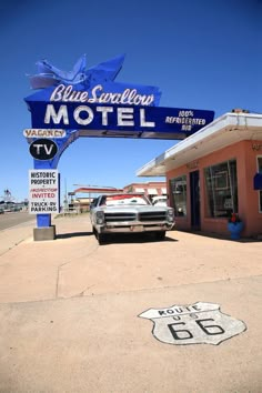 a motel sign and car parked in front of it