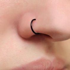 a woman's nose with a single black ring on the tip of her nose