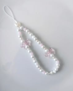 a white beaded necklace with pink flowers and pearls hanging from it's end