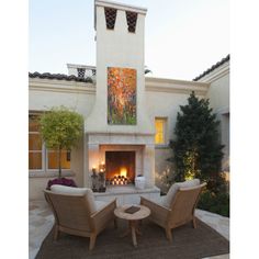 two chairs sitting in front of a fire place with a painting on the wall above it