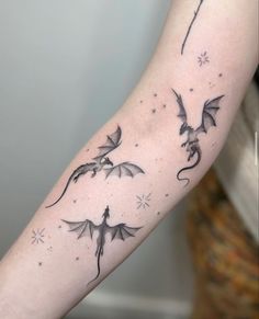 a woman's arm with three flying dragon tattoos on the left forearm and right arm