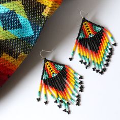 Hand woven by indigenous Embera Chami artisans, these seed bead earrings represent a piece of Colombian culture, fusing modern designs with ancient tribal craftsmanship. The Embera Chami tribe are known for their intricate and colorful bead work and these earrings do not disappoint. Each pair features beautiful bead detailing in a unique FOSTERIE exclusive small batch pattern. Materials: Seed beadsSize: Approximately 3 inches from top of hook, 1.5 inch wide Multicolor Teardrop Jewelry For Crafting, Multicolor Handwoven Dangle Jewelry, Traditional Handwoven Black Jewelry, Traditional Black Handwoven Jewelry, Modern Handmade Jewelry For Festivals, Modern Handmade Festival Jewelry, Artisan Black Jewelry With Ear Wire, Modern Handmade Rainbow Jewelry, Black Beaded Earrings With Ear Wire For Festival