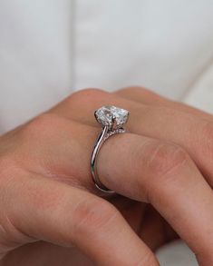 a close up of a person's hand with a diamond ring on their finger