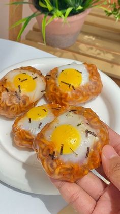 three fried eggs are being held on a white plate with chopsticks in it