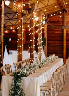 a long table with white linens and greenery is set up for an event