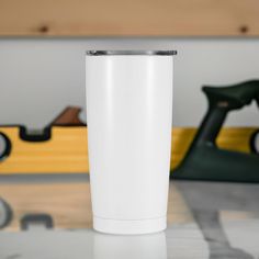 a white tumbler sitting on top of a table next to a yellow and black toy