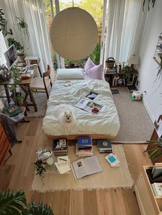 a room with a bed, books and plants on the floor