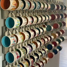 a wall mounted coffee cup rack with cups hanging on it's sides and two rows of mugs in the middle