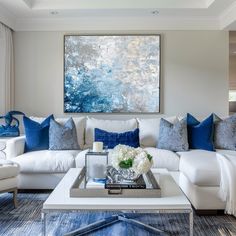 a living room filled with white furniture and blue pillows