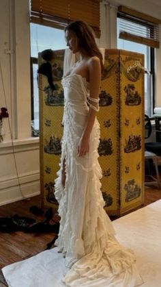 a woman in a white dress is standing on a mat and looking out the window