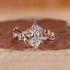 a close up view of a diamond ring on top of a piece of brown leaf