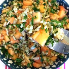 a blue bowl filled with rice, carrots and other veggies next to a spoon