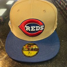 a red sox hat sitting on top of a counter next to a baseball cap with the word reds written on it