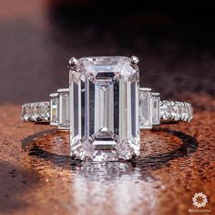 an emerald - cut diamond ring sits on a table