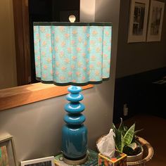 a blue lamp sitting on top of a table next to a basket filled with books