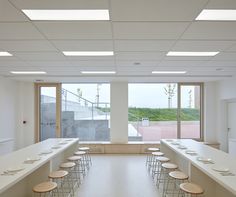 an empty room with tables and chairs in front of large windows