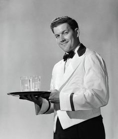 a man holding a tray with two glasses on it