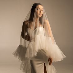 a woman in a white dress and veil posing for the camera with her hands on her hips