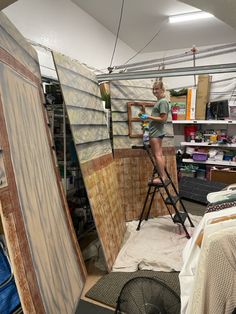 a woman standing on top of a ladder in a room