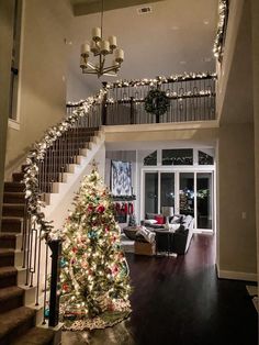 a decorated christmas tree in the middle of a living room with stairs leading up to it