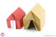 an origami house next to a folded up paper house on a white background