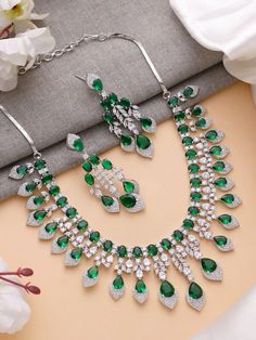 Add a touch of glamour and sophistication with this high quality necklace set in beautiful emerald green stones. The stones in this set bling and look close to the real thing. This set is sure to make heads turn! 
It features an adjustable necklace and a pair of earrings. It can be paired perfectly with both ethnic and western outfits. 
In case of any queries, please feel free to reach out. Happy shopping! Green Sparkling Stones Jewelry Sets For Party, Cubic Zirconia Emerald Necklace For Wedding, Hand Set Crystal Emerald Necklace For Wedding, Wedding Emerald Crystal Necklace Hand Set, Dazzling Green Jewelry With 17 Jewels, Silver Emerald Jewelry Sets For Wedding, Dazzling Green Emerald Necklace, Dazzling Green Emerald Necklace For Anniversary, Green Emerald Jewelry With Sparkling Stones