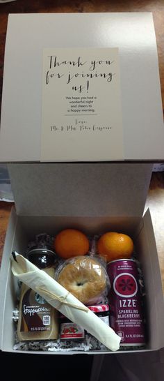 an open box containing oranges, yogurt and other food items on a table