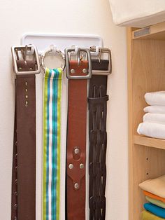 three belts are hanging on the wall next to folded towels