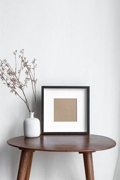 a white vase sitting on top of a wooden table next to a black and white photo