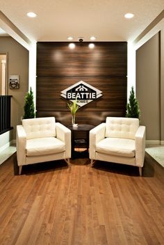 a couple of white chairs sitting in front of a sign on a wooden paneled wall