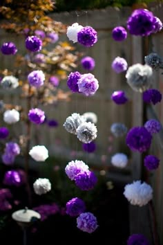 purple and white paper flowers hanging from a tree