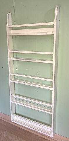 an empty white shelf in the corner of a room with green walls and wood flooring