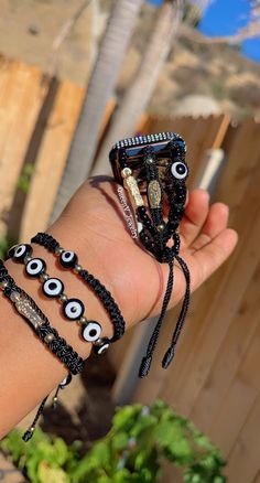 a hand holding three bracelets with evil eyes on them and beads around the wrist