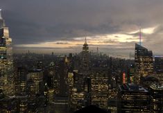 the city skyline is lit up at night, with skyscrapers in the foreground