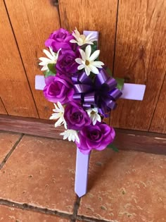 purple and white flowers are tied to a cross