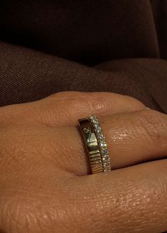 a woman's hand with a gold ring and diamond band on her left wrist