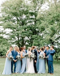 a group of people standing next to each other in front of some trees and grass