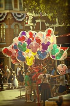 a bunch of balloons in the shape of mickey mouses are being carried by people