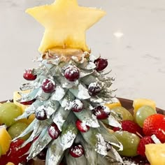 a christmas tree made out of fruit on a platter with a star in the top