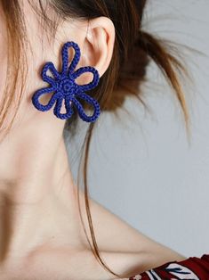 a close up of a person wearing earrings with an object in the shape of a flower