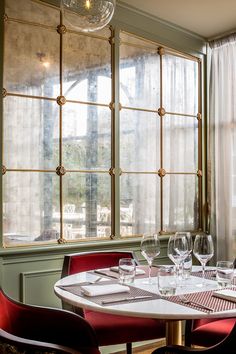 the table is set with wine glasses and place settings in front of an open window