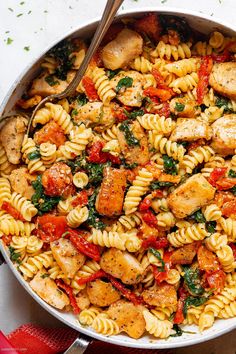 pasta with chicken, spinach and tomatoes in a skillet ready to be eaten