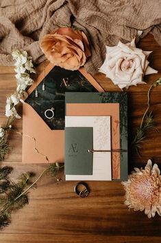 the wedding stationery is laid out on top of the table with flowers and greenery