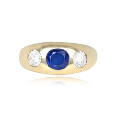 a yellow gold ring with an oval blue sapphire and three diamonds