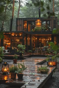 a house made out of shipping containers with lights on the windows and plants in pots