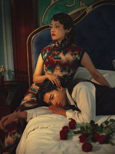 a woman laying on top of a bed next to a man in a black suit