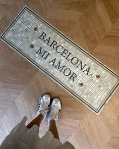 a person standing in front of a door mat that says barcelona mamor on it