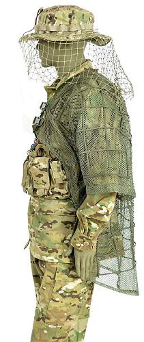 a soldier in camouflage is wearing a netted face mask and holding his hand on his hip