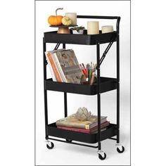 a three tiered shelf with books and candles on it, next to a candle holder